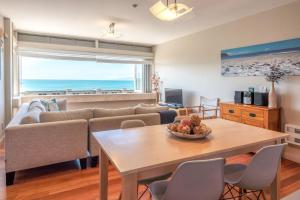 uma sala de estar com uma mesa e um sofá em The Sands - Apartment 15 - Stay Waiheke em Onetangi