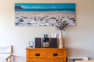 uma cômoda de madeira com alto-falantes e um quadro na parede em The Sands - Apartment 15 - Stay Waiheke em Onetangi