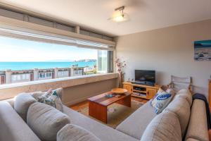 uma sala de estar com um sofá e uma janela grande em The Sands - Apartment 15 - Stay Waiheke em Onetangi