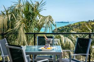 a table with a drink on top of a balcony at Delamore Cove - Manuka - Stay Waiheke in Matiatia Bay +10 photos