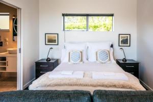 a bedroom with a large bed and a window at Delamore Cove - Manuka - Stay Waiheke in Matiatia Bay