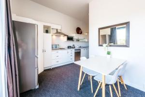 a small kitchen with a white table and chairs at Delamore Cove - Manuka - Stay Waiheke in Matiatia Bay