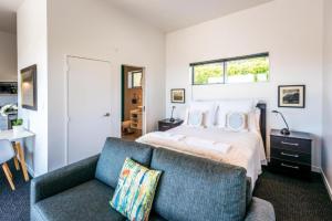 a bedroom with a bed and a blue couch at Delamore Cove - Manuka - Stay Waiheke in Matiatia Bay