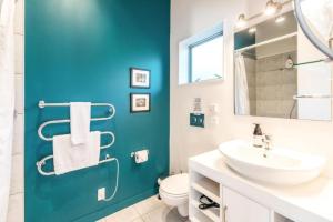 a bathroom with a white sink and a blue wall at Delamore Cove - Manuka - Stay Waiheke in Matiatia Bay