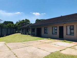 a house with a grass yard in front of it at Mhlezi Lodge in Richards Bay