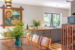 a kitchen with a table and a painting on the wall at Treetop Escape - Stay Waiheke in Waiheke Island