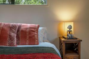 a bedroom with a bed and a lamp on a table at Treetop Escape - Stay Waiheke in Waiheke Island +19 photos