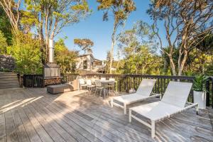 a patio with chairs and a grill and trees at Skyview Onetangi - Stay Waiheke in Waiheke Island