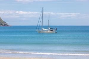 a boat floating in the water on a beach at The Sands Apartment 8 - Stay Waiheke in Waiheke Island +27 photos