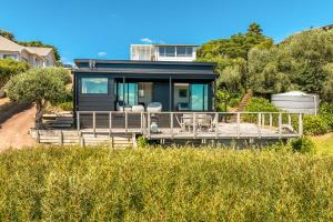 a house sitting on top of a grass field at Black Cottage - Stay Waiheke in Waiheke Island