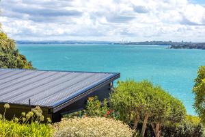 a house with a view of a large body of water at Black Cottage - Stay Waiheke in Waiheke Island +24 photos