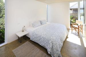 a white bedroom with a bed and a window at Number Five - Stay Waiheke in Onetangi