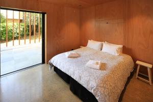 a bedroom with a bed with two towels on it at Number Five - Stay Waiheke in Onetangi