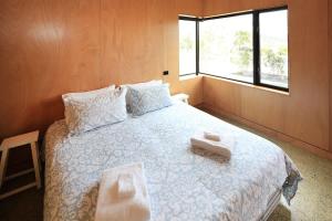 a bedroom with a bed with two towels on it at Number Five - Stay Waiheke in Onetangi +2 photos
