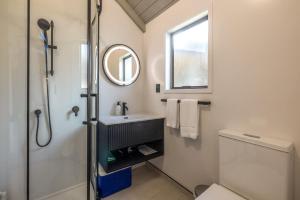 a bathroom with a sink and a mirror and a toilet at Hibiscus Hideaway - Stay Waiheke in Palm Beach