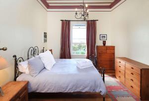 Crescent Villa - Stay Waiheke في Ostend: غرفة نوم بسرير وخزانة ونافذة