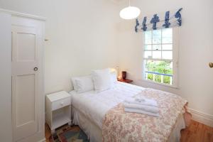 Crescent Villa - Stay Waiheke في Ostend: غرفة نوم بها سرير مع مناشف عليه