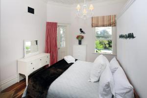 Crescent Villa - Stay Waiheke في Ostend: غرفة نوم بسرير وخزانة وتلفزيون
