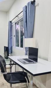 ein Laptop auf einem weißen Schreibtisch mit einem Stuhl in der Unterkunft Mountain view Villa Private Tropical Garden in Chiang Dao