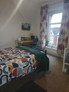 ein Schlafzimmer mit Bett, Schreibtisch und Fenster in der Unterkunft Uplands Room in Sketty