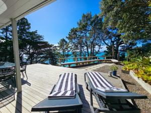 two lounge chairs on a deck with a view of the water at Viewpoint - Stay Waiheke in Onetangi