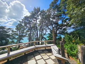 a person standing on a wooden bridge with trees in the background at Viewpoint - Stay Waiheke in Onetangi +13 photos