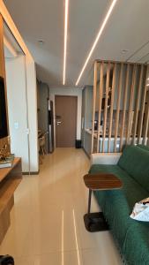 Una sala de estar con un sofá verde y un televisor. en Charming apartment with balcony a few minutes apto from Barra, en Salvador
