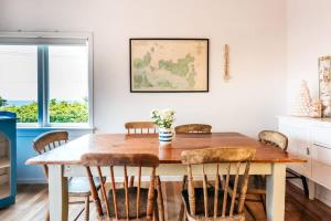 a dining room with a wooden table and chairs at Sunshine Cottage by the Sea - Stay Waiheke in Onetangi