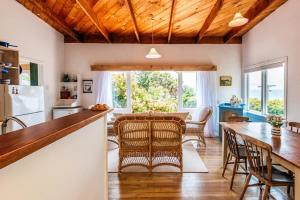 a kitchen and dining room with a wooden ceiling at Sunshine Cottage by the Sea - Stay Waiheke in Onetangi