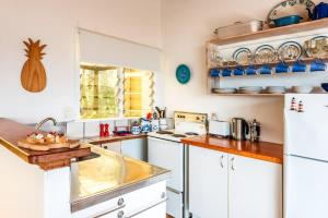 a kitchen with white cabinets and a white refrigerator at Sunshine Cottage by the Sea - Stay Waiheke in Onetangi