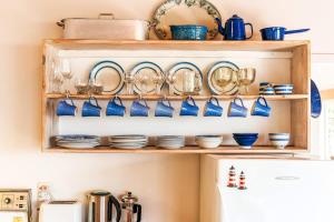 a shelf with blue dishes and plates on it at Sunshine Cottage by the Sea - Stay Waiheke in Onetangi +24 photos