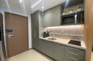 una cocina con fregadero y microondas en Charming apartment with balcony a few minutes apto from Barra, en Salvador 28 fotos más