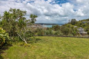 a field of grass with a view of the water at Church Bay Views - Stay Waiheke in Oneroa