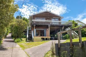 a house with a wrap around porch and a deck at Church Bay Views - Stay Waiheke in Oneroa