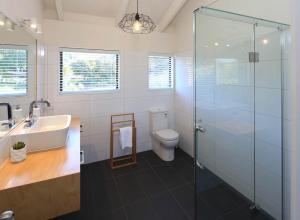 een badkamer met toilet en glazen douche bij Church Bay Views - Stay Waiheke in Oneroa