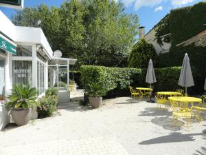 un patio con tavoli, sedie e ombrelloni di Hotel de l'île ad Avignone