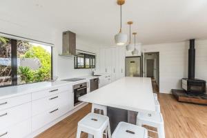 een keuken met witte kasten en een tafel en stoelen bij Sunset Sanctuary- Stay Waiheke in Omiha