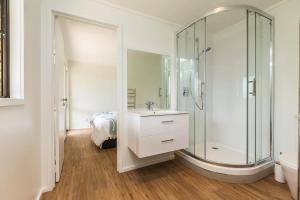 een badkamer met een glazen douche en een wastafel bij Sunset Sanctuary- Stay Waiheke in Omiha