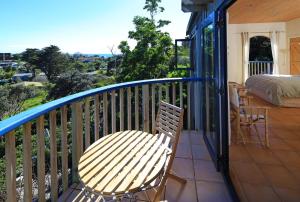 a balcony with a bed and a wooden table and chair at La Maisonette - Stay Waiheke in Onetangi