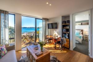 a living room with a bed and a room with a table at Wavesong - Stay Waiheke in Onetangi