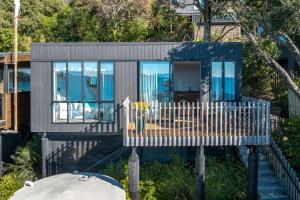 a small house with a white picket fence at Wavesong - Stay Waiheke in Onetangi