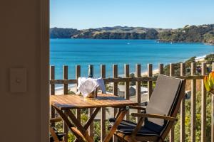 a table and chair on a balcony with a view of the water at Wavesong - Stay Waiheke in Onetangi