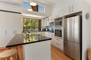 a kitchen with white cabinets and a stainless steel refrigerator at The Cove at Little O - Stay Waiheke in Oneroa