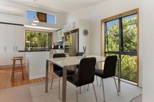 a kitchen and dining room with a table and chairs at The Cove at Little O - Stay Waiheke in Oneroa