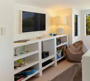 a living room with a white entertainment center with a tv at The Cove at Little O - Stay Waiheke in Oneroa