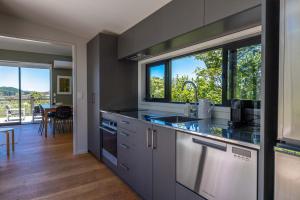 uma cozinha com um lavatório e uma grande janela em Art Lovers Retreat - Stay Waiheke em Onetangi