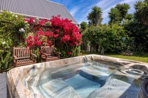 a swimming pool in a yard with pink flowers at Alhambra - Stay Waiheke in Oneroa