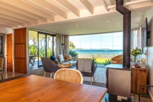 a living room with a table and a view of the ocean at Alhambra - Stay Waiheke in Oneroa +41 photos
