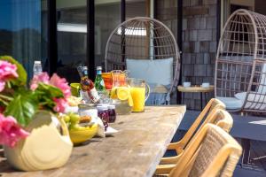 a wooden table with drinks and flowers on a patio at Alhambra - Stay Waiheke in Oneroa