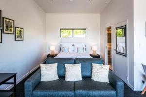 a bedroom with a blue couch in front of a bed at Delamore Cove - Kauri - Stay Waiheke in Matiatia Bay